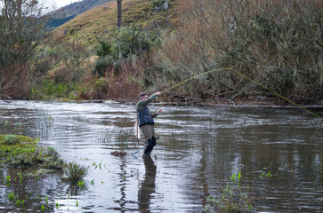 Fisherman fly fishing rainbow trout on mountain in beautiful scenic