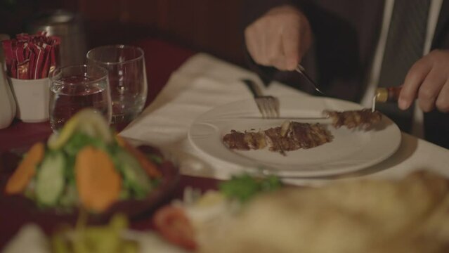 A man who tastes the horizontally cooked kebab typical of Turkish food culture and the products served with it at the dinner table.