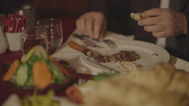 A man who tastes the horizontally cooked kebab typical of Turkish food culture and the products served with it at the dinner table.