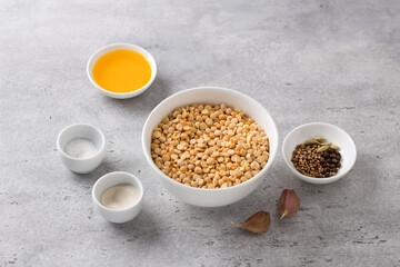 Ingredients for delicious homemade vegan pea sausage: dry peas, salt, agar agar, vegetable oil, spices, garlic on a gray textured background