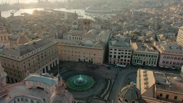 Establishing aerial panorama of Central Genoa City, Italy, Europe. Landmark Piazza De Ferrari with Opera and Palace of the Doges at sunset. Urban Travel and Architecture concept. 4K orbit drone shot