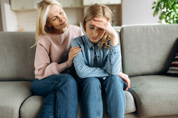 Naklejka na ściany i meble Worried mature mother consoles her adult daughter, helping with problem and depression, caring she, empathy, support in two age generations. Support of a loved one