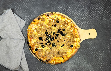 tuna pizza with cheese and tomato and olives on cutting wooden board 