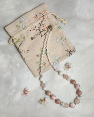 Handmade glass necklace. porcelain and stone and storage bag, composition with women's jewelry, selective focus, vertical orientation.