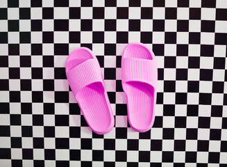 Female pink slippers on checkered black and white squares background. Relaxation minimal concept.