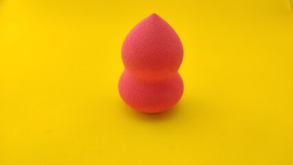 pink beauty blender on yellow background