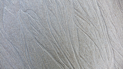 Sand background and texture. Wet beach sand texture after low tide. Sand with wave print. Ripple on the beach sand. 