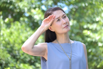 日差しの強い公園で紫外線を気にするシニア女性