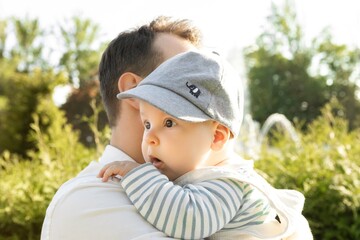 father holding his son in his arms on a background of greenery