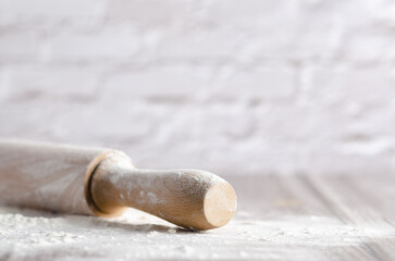 A rolling pin with white flour on wooden background. Copy space. 