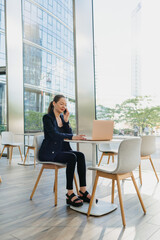 A female realtor in a blazer is working at the table in the modern lobby