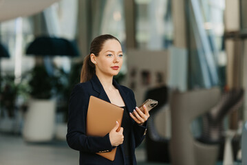 A female realtor in a blazer is working at the table in the modern lobby