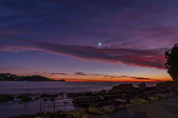 First light over the ocean with 9 percent sliver of moon, stars and planets