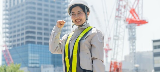 ガッツポーズをする笑顔でカメラ目線の工事現場で働く女性