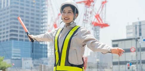 誘導棒を持つ笑顔の工事現場で働く日本人女性