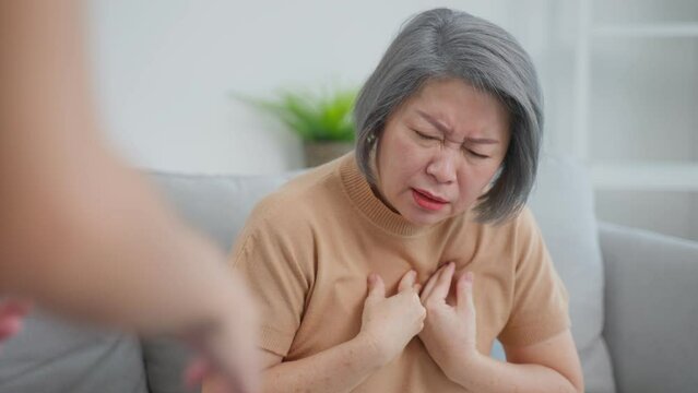 Asian daughter help senior mother having chest pain from heart attack