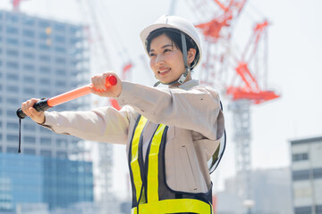 誘導棒を持つ笑顔の工事現場で働く日本人女性