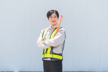 誘導棒を持ち作業服を着る日本人女性