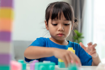 Adorable little girl playing toy blocks in a bright room