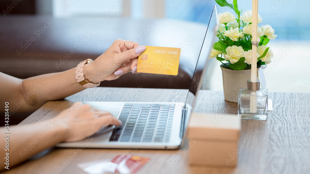 Wall mural close-up woman holding credit card and use laptop for purchase product on internet in home office, p