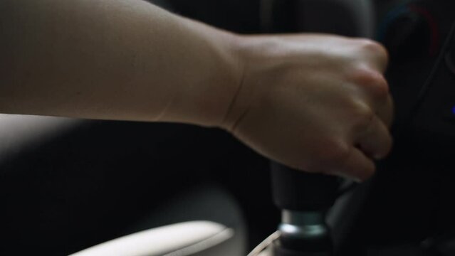 Woman's hand reaches into frame and shifts gears on manual transmission. Slow mo. Close up.
