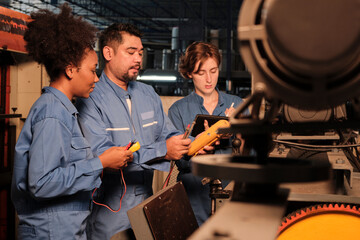 Multiracial professional industry engineer teams in safety uniforms work by inspecting machines' voltage current, checking, and maintaining at manufacture factory, electric system service occupations.