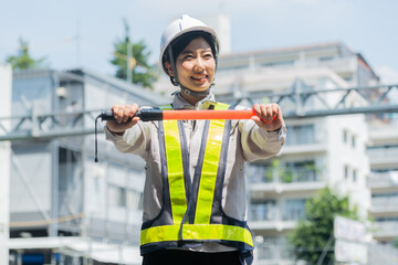 誘導棒を持ち工事現場で働く女性