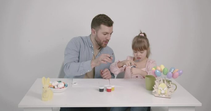 Girl with down syndrome painting Easter eggs with father