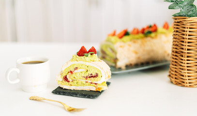 Piece of meringue roll with strawberries on a plate with a cup of tea.
