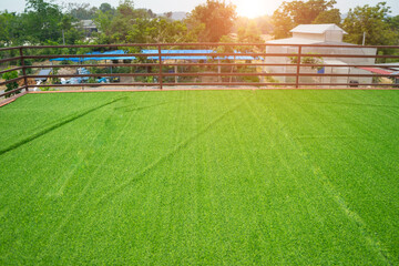 Soft focus and blurred of field turf or artificial grass soccer field, green lawn on the top of the roof with steel fence and sunlight background.