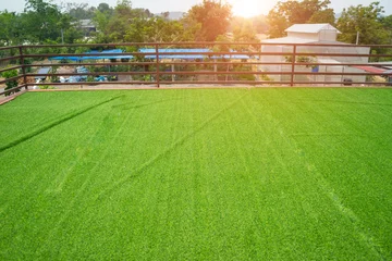 Fotobehang Soft focus and blurred of field turf or artificial grass soccer field, green lawn on the top of the roof with steel fence and sunlight background. © sornchai