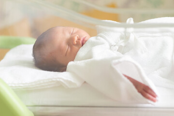 ベビーコットで寝ている新生児