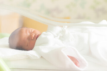 Obraz na płótnie Canvas ベビーコットで寝ている新生児