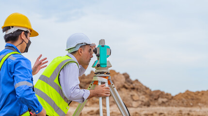 Surveyor engineer wearing safety uniform and helmet with equipment theodolite to measurement...