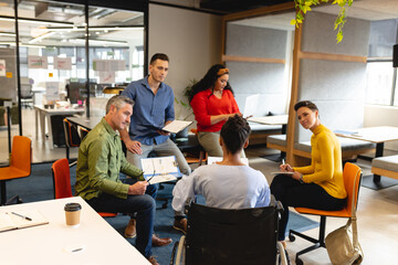 Multiracial businessmen and businesswomen discussing in meeting at creative office