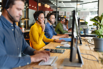 Smiling caucasian female customer service executive talking through headset in office