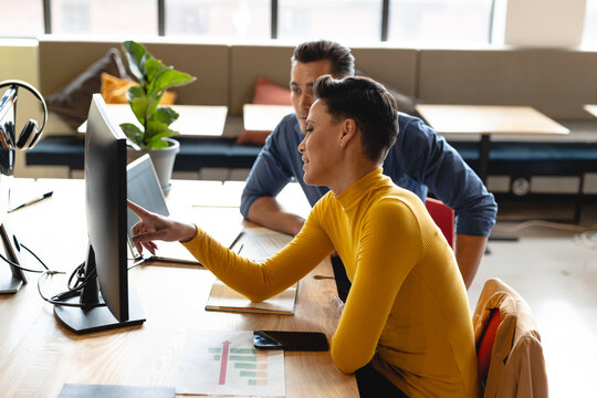 Multiracial businessman and businessman discussing over computer in creative office