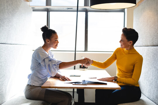 Multiracial businesswomen handshaking during meeting in creative office