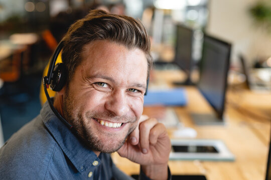 Portrait of smiling caucasian male customer service executive with headset in office