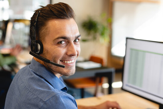 Portrait of smiling caucasian male customer service executive with headset in office