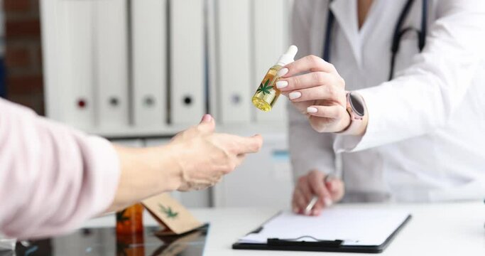 Closeup of doctor hands giving bottle of cannabinoid oil to doctor