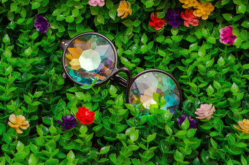 designer glasses with kaleidoscope lenses on green artificial grass with flowers