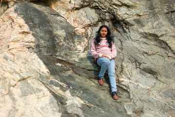 an Indian young woman sitting on a mountain rock peacefully in winter and enjoy the sunlight.