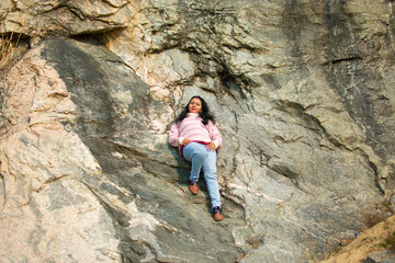 an Indian young woman sitting on a mountain rock peacefully in winter and enjoy the sunlight.
