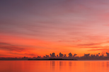 Naklejka premium Peaceful sunrise, colorful sky and sea, island on horizon.