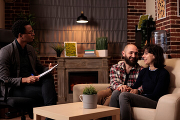 Married people feeling happy about reconciliation and solving relationship issues with help from male therapist. Attending couple therapy to receive counseling advice, holding hands.