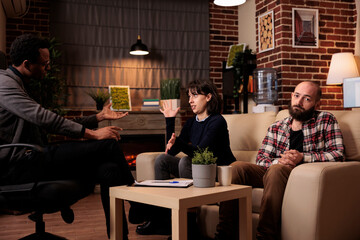 Man and woman attending psychotherapy session with counselor to solve couple problems together. Talking about relationship difficulties with therapist to stop fight and save marriage.
