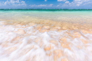 Soft crystal clear wave of blue ocean on sandy beach. Selective focus.