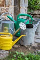 Group of garden watering can in front of stone well during drought