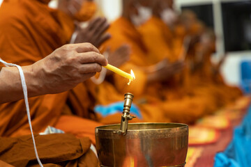 Thai traditional style making holy water in from buddha monk. Close-up in hand buddhism monk holding  candle lighting and drippings into  holy water bowl.